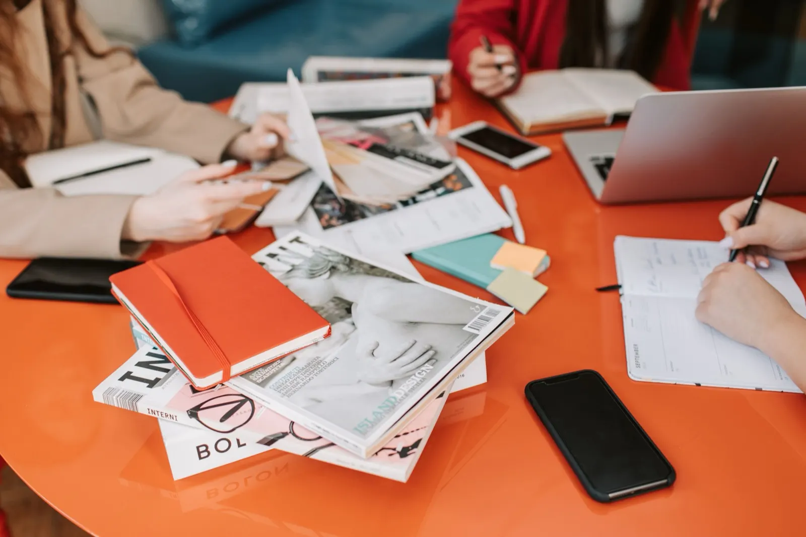 Mesa naranja con cuadernos, revistas y notas de estudio