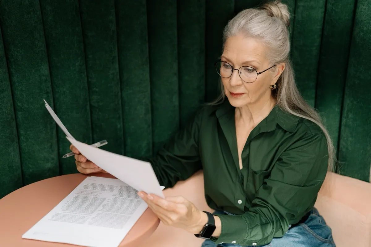 Mujer mayor revisando documentos en una mesa
