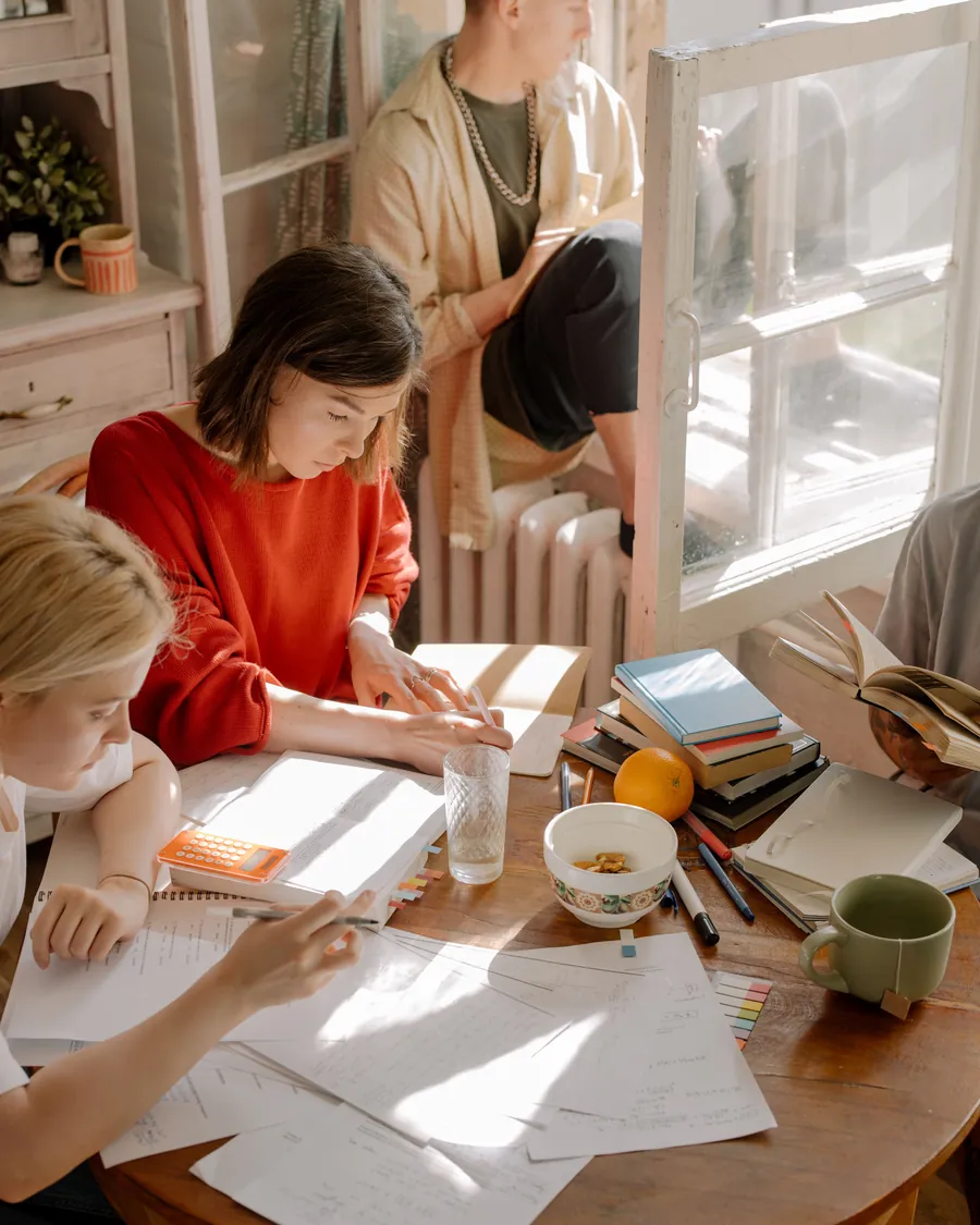 Opositores estudiando con sus apuntes y libros sobre una mesa, con luz natural